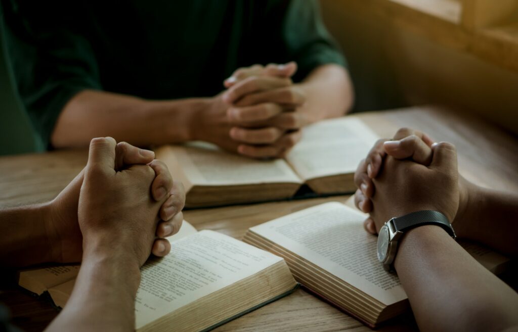 Group of christian people reading and study bible in home and pray together.
