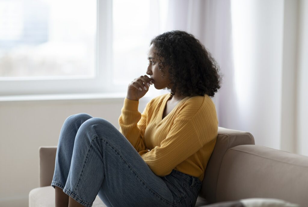 Mental health care. Depressed young black woman suffering from emotional burnout on couch at home